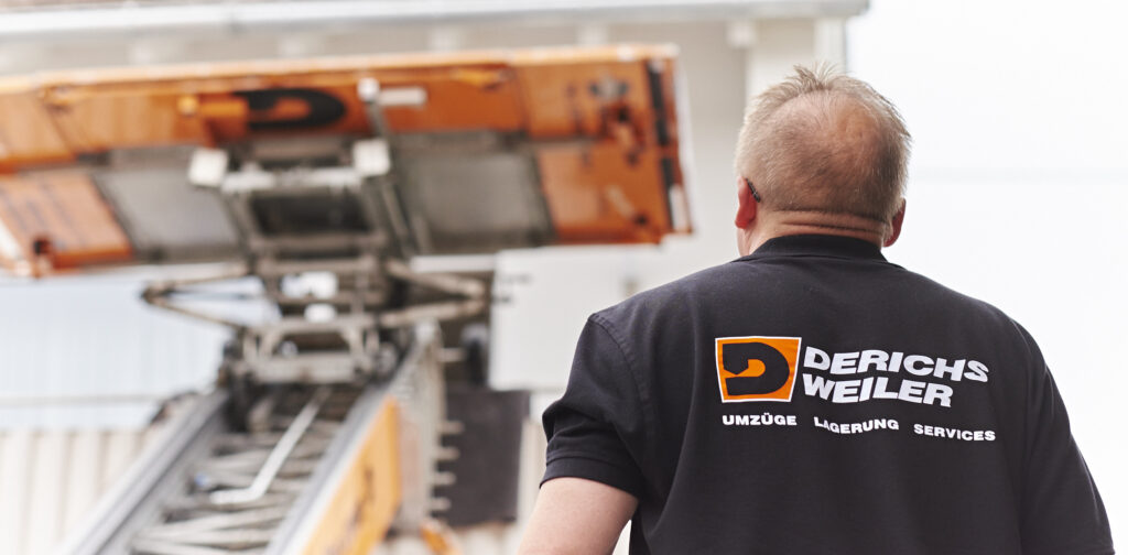 Derichsweiler Mitarbeiter beobachtet einen beweglichen Aufzug, der Gegenstände in ein oberes Stockwerk eines Gebäudes transportiert.