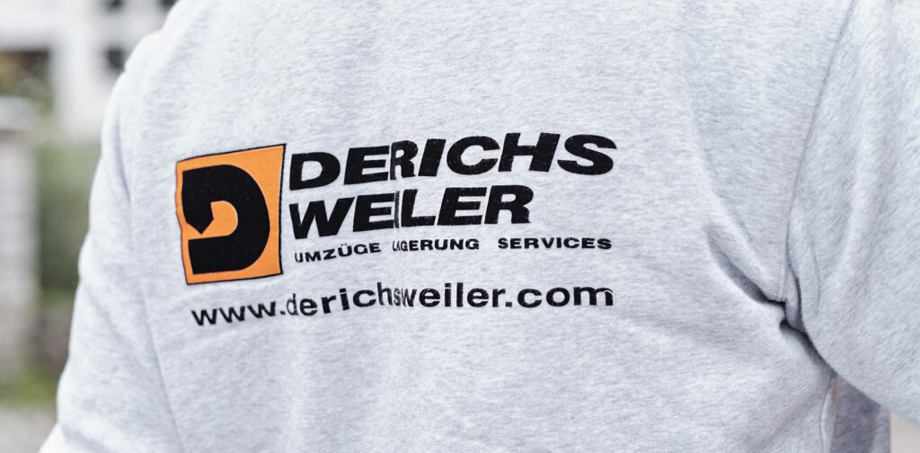 Eine Person, die ein hellgraues Sweatshirt mit dem Derichsweiler Logo trägt.