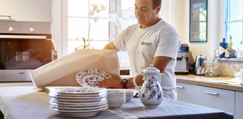 Unser Mitarbeiter verpackt sorgfältig blau-weißes Porzellan in einer Küche.
